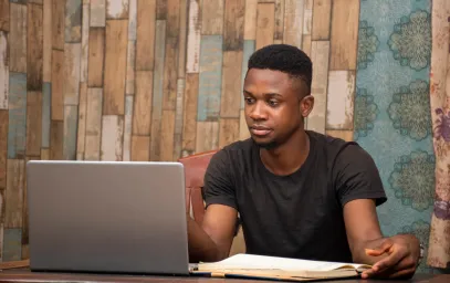 Young man studying with book and computer
