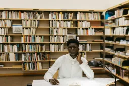 man sitting at desk with shelves of books behind him