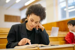 Young female student reading book in lecture theatre